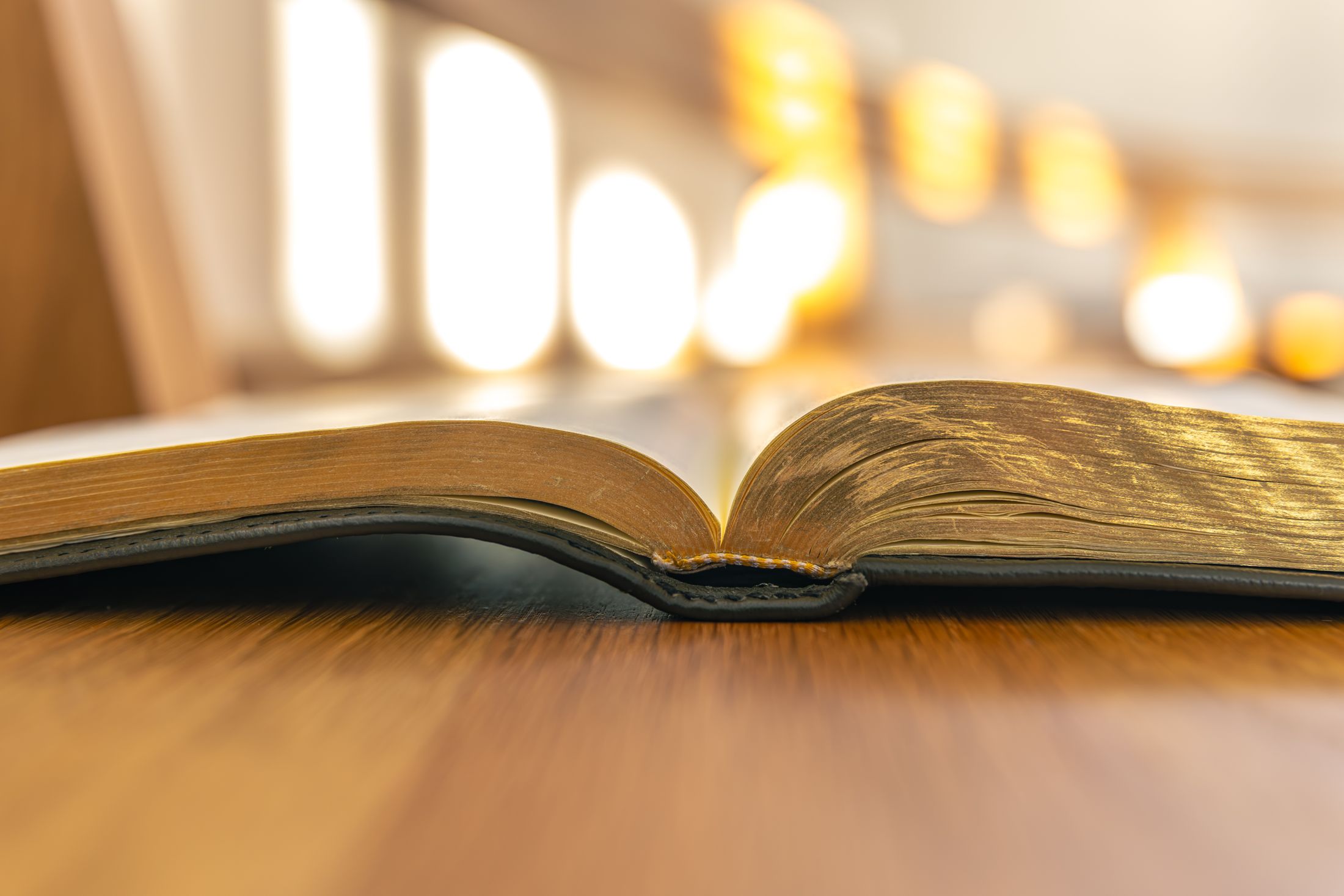 An open Bible on a wooden table in warm light